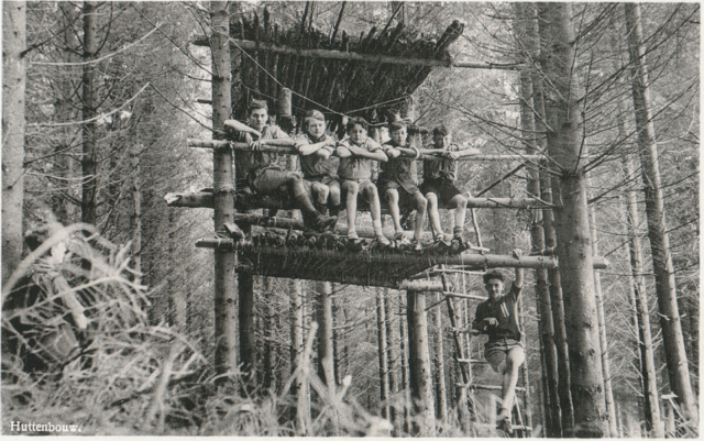 een oude foto van een groep scoutsjongens die in hun boomhut zitten.