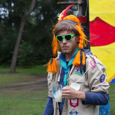 Scoutsleider in uniform met drankje in zijn hand.