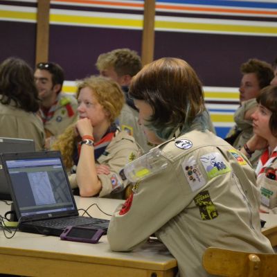leiding in uniform in een lokaal allemaal over laptops gebogen