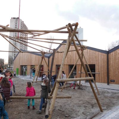 Kinderen die samen met scoutsleiders een grote constructie aan het sjorren zijn.