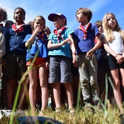 groepje scouts en gidsen met rood-witte das staan klaar om een spel te starten. 
