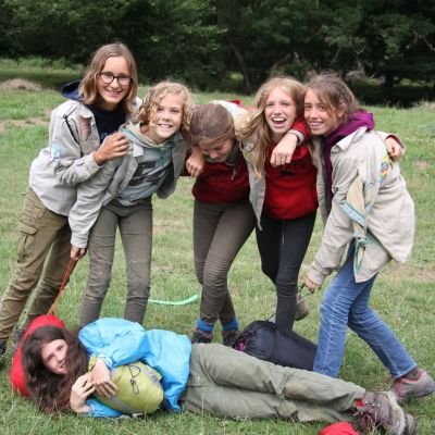 zes jonggidsen poseren met hun slaapzak, eentje ligt plat op de grond