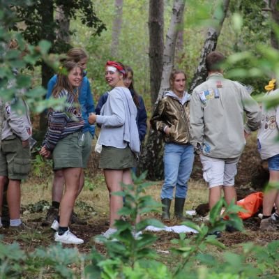 Groepje leiding staan in een kring in het bos op Herfstontmoeting