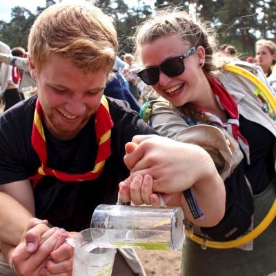 Leider en leidster spelen een spel met water doorgeven op Herfstontmoeting