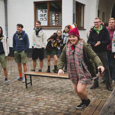 Scoutsleiding staan in twee groepjes op de binnenplaats van De Kluis. Klaar voor een spel. Van een groep begint iemand te lopen.