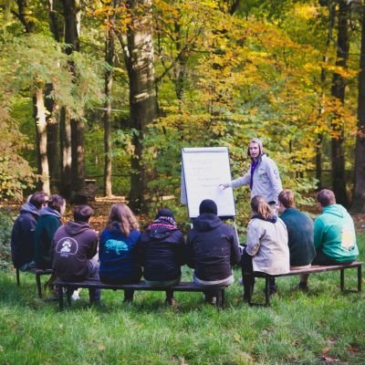 animators in spé zittend op bankjes in het bos rond een flipchart