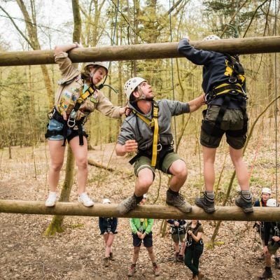 Drie leiders zijn beveiligd en helpen elkaar op het touwenparcour op Jeugdverblijf De Kluis.