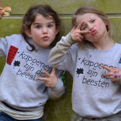 Twee kapoenen tegen een muur die een duckface maken en peace tekens opsteken