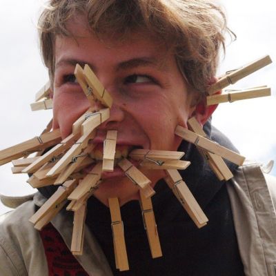 jongen met veel wasknijpers op zijn gezicht
