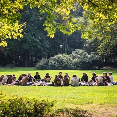 Trijn Nyckees Een scoutsgroep in een cirkel zit op het gras onder de zon in het park