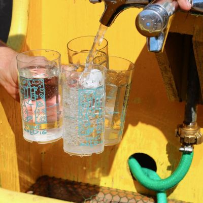Drie Herfstontmoetingsbekers worden aan een kraantje gevuld met water.