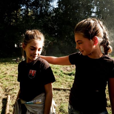 Een gids legt haar arm om een andere beiden glimlachen. Achteraan zijn anderen aan het sjorren.