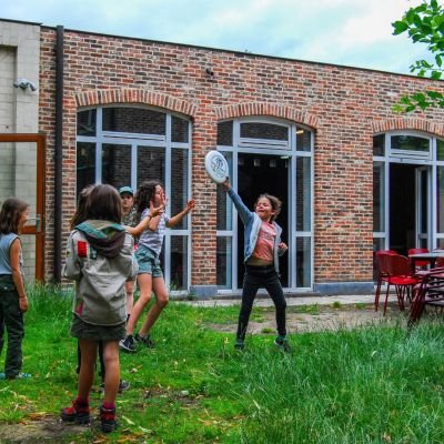 Hana Reynaert Leden spelen in het gras voor hun scoutslokaal
