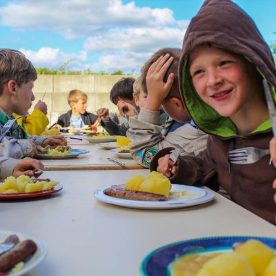 Welpen zitten aan gesjorder tafel te eten op kamp