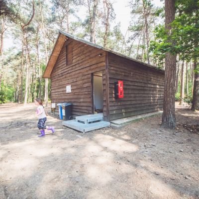 Twee kinderen die naar buiten zijn gekomen uit een blokhut in een bos.