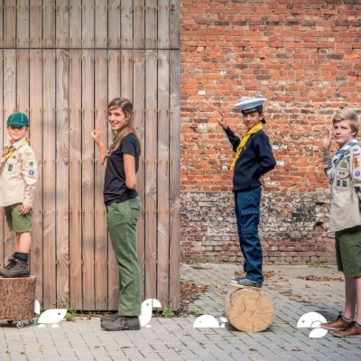 scouts en gidsen poserend in allerlei vormen van het scoutsuniform 