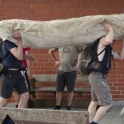2 mensen dragen een grote opgerolde tent