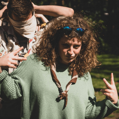 Coole leidster met zonnebril in de haren doet het V-teken met haar handen.