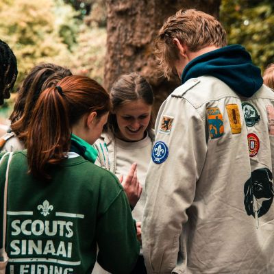 leden en leiding staan in een kringetje voorovergebogen