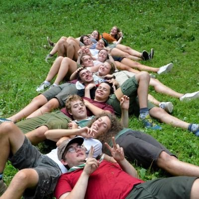 Scoutsleden liggend in het gras, hoofd op elkaars buik.