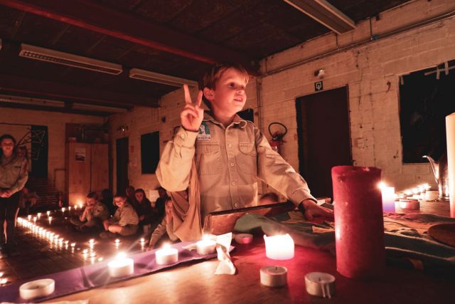 Een welp legt zijn belofte af. Een hand in welpengroet het andere hand op de scoutsvlag.