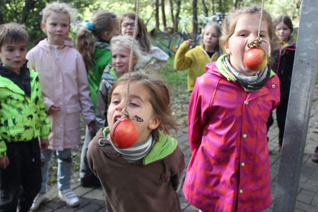 Twee kapoenen bijten in appels die bungelen aan touwtjes