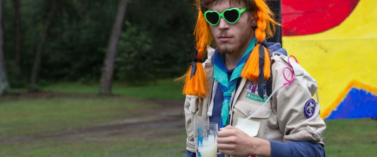 Floor Bruggeman Scoutsleider in uniform met drankje in zijn hand.