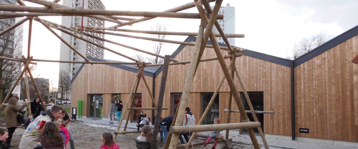 Kinderen die samen met scoutsleiders een grote constructie aan het sjorren zijn.