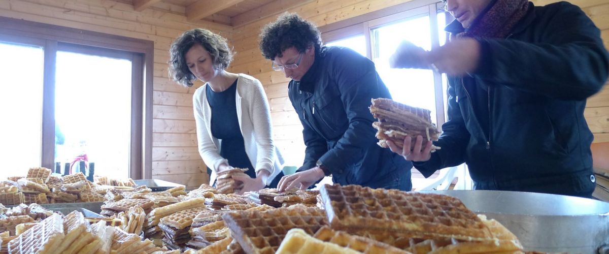 Drie ouders stapelen en tellen wafels uit een hoop vers gebakken wafels