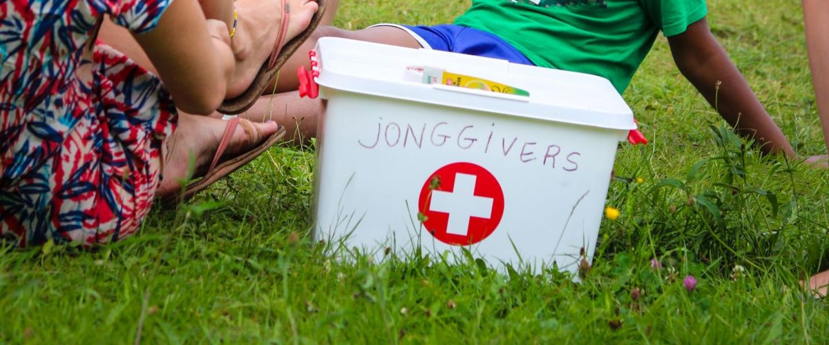 Trijn Nyckess Twee leden zitten naast in het gras een EHBO-koffer op kamp.