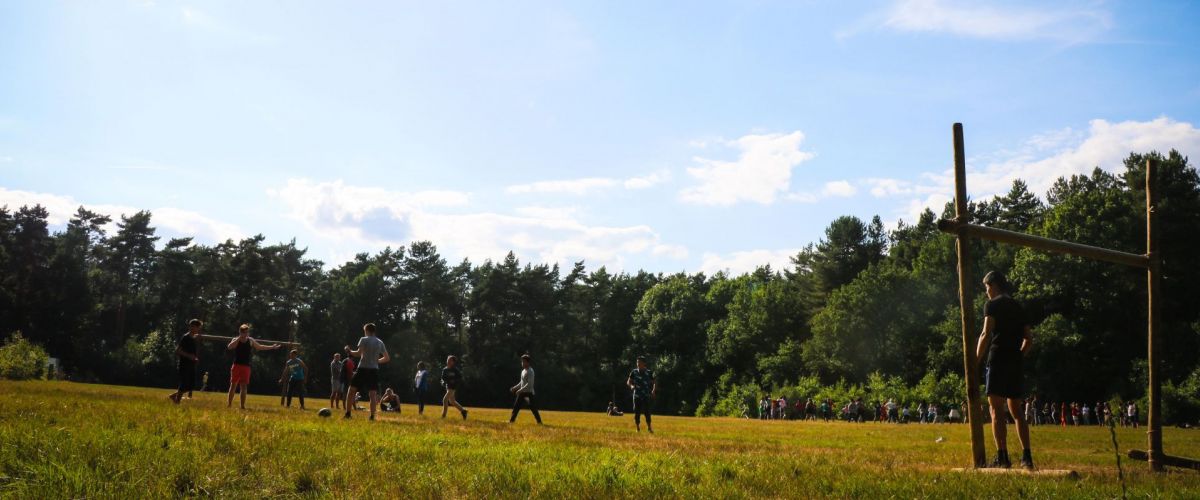 Groepje jongeren aan het voetballen op een veld met gesjorde goals.