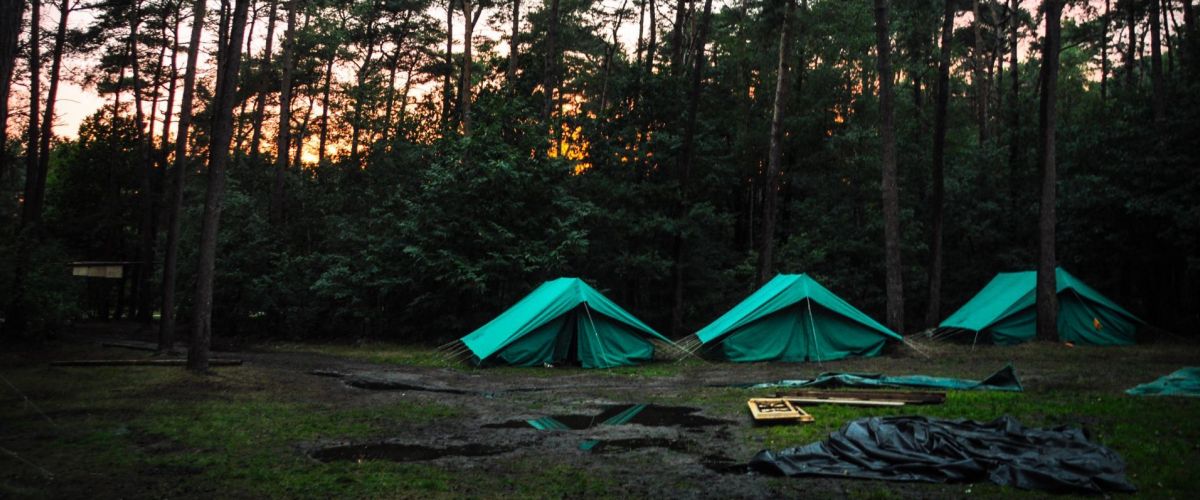 3 patrouilletenten onder de bomen bij zonsondergang