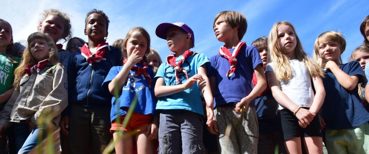 groepje scouts en gidsen met rood-witte das staan klaar om een spel te starten. 