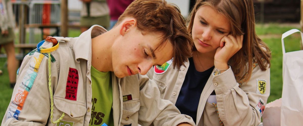 scout en gids overleggen. De scout noteert iets.