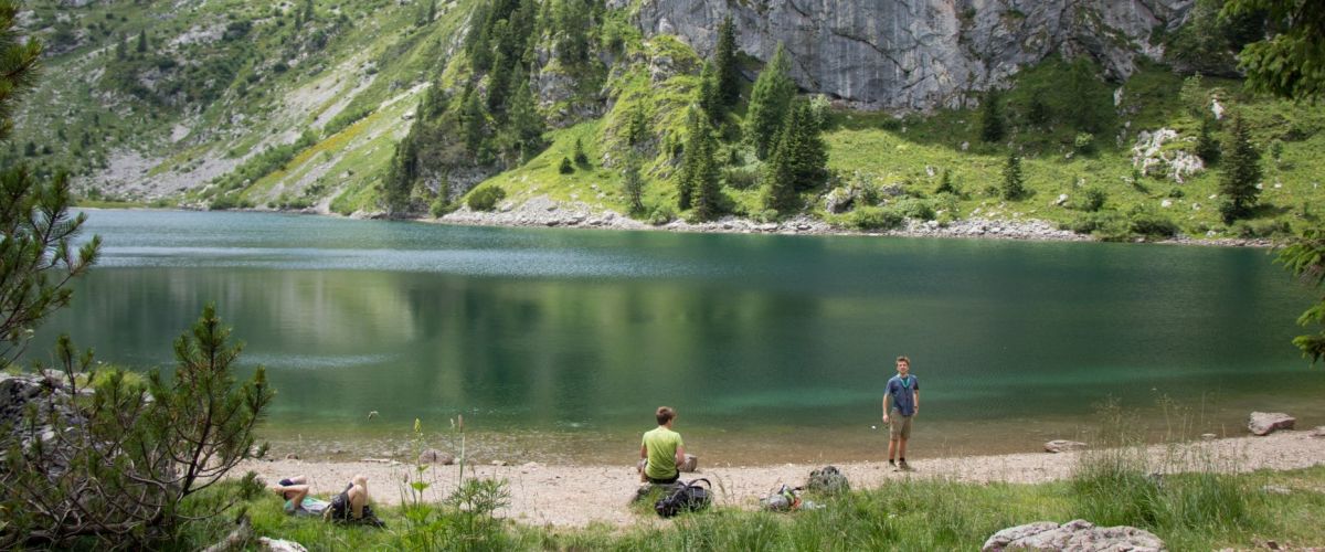 drie scouts rusten aan een bergmeer 