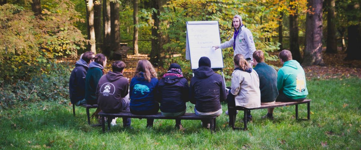 Joke Van der Maelen animators in spé zittend op bankjes in het bos rond een flipchart