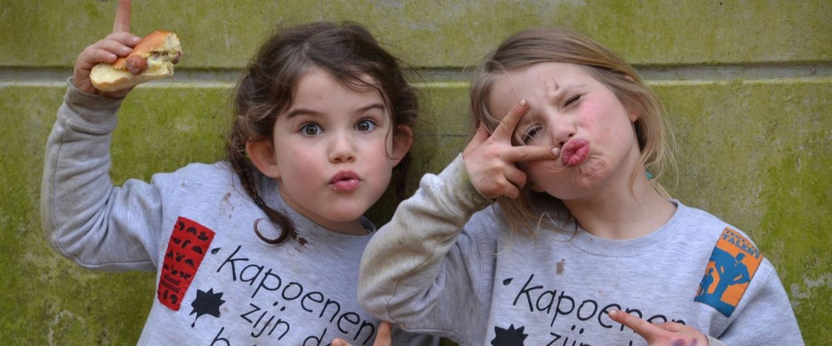 Twee kapoenen tegen een muur die een duckface maken en peace tekens opsteken