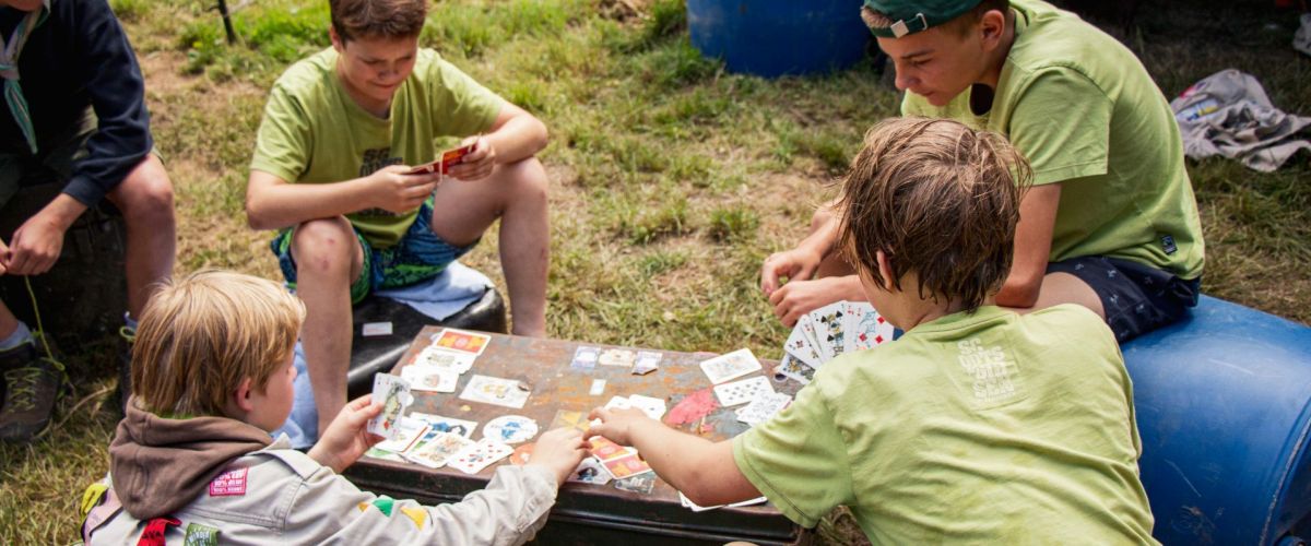 Vier jonggivers kaarten op kamp