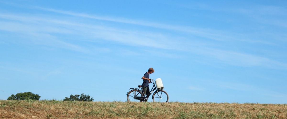 Giver met waterbidon op zijn fiets, op kamp.