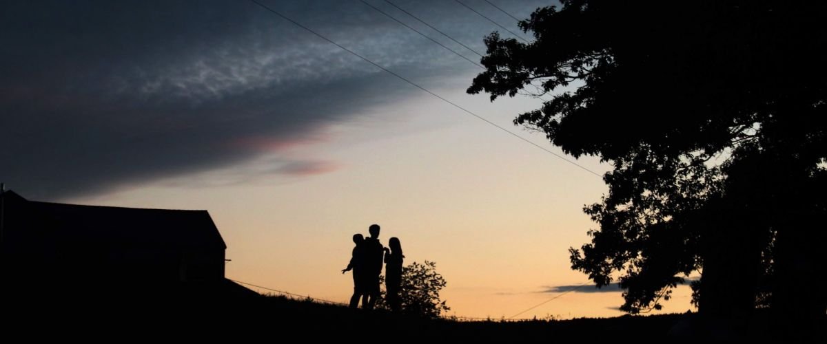 drie scouts staan bij valavond naast een boom