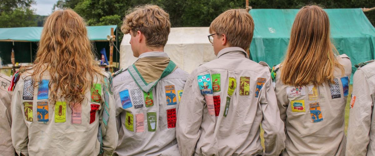 4 givers, rachterzijde scoutshemden met veel jaarkentekens
