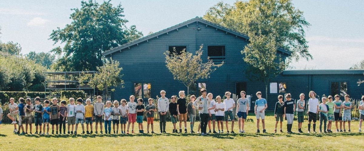 Groep leden staat op een lijn voor hun lokaal in latem