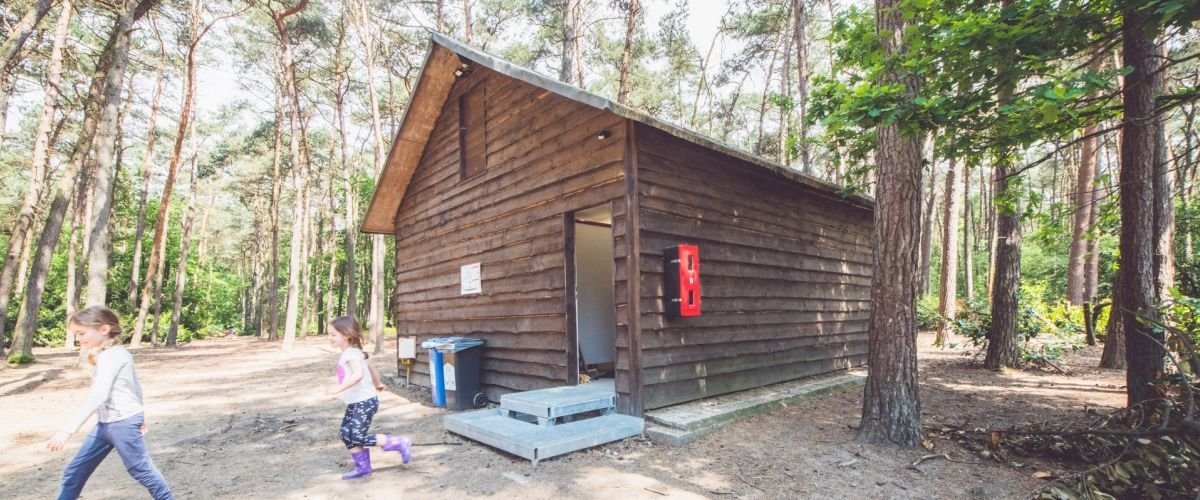 Twee kinderen die naar buiten zijn gekomen uit een blokhut in een bos.