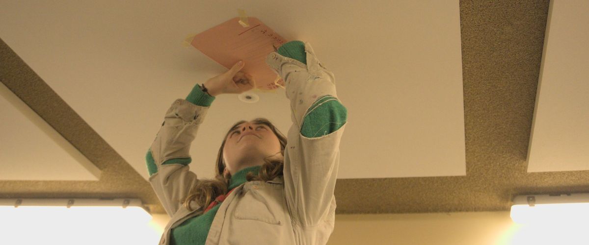 Fotograaf: Alexander Janssens Leiding schrijft op een papier tegen het plafond.