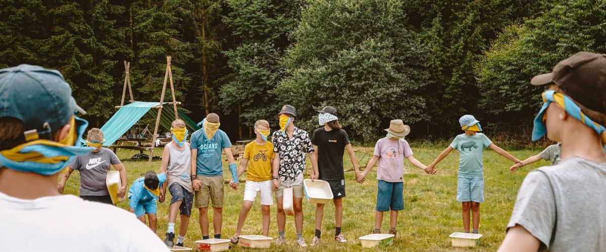 Jonggivers in een kring met blinddoek op op kamp