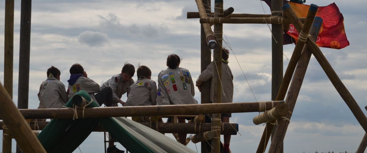 Leden zitten op een gesjorde constructie op zomerkamp