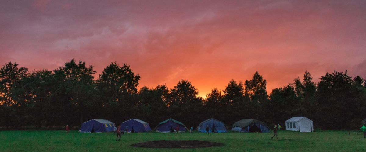 tenten aan de bosrand onder een ondergaande zon