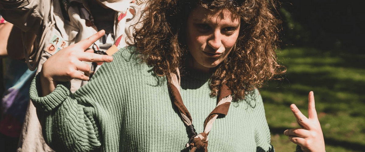 Coole leidster met zonnebril in de haren doet het V-teken met haar handen.