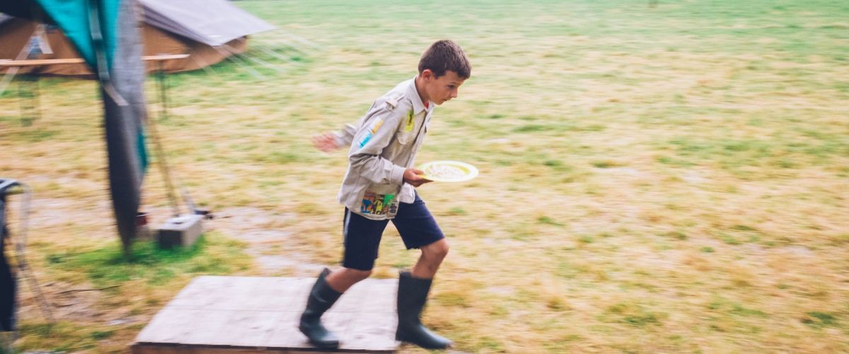 Jonggiver die door de regen naar de tent loopt