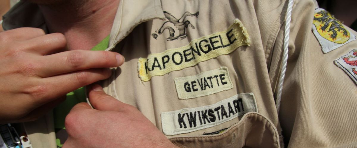 Roel Velkeneers een leider met totem kapoengele gevatte kwikstaart knoopt zijn scoutshemd toe